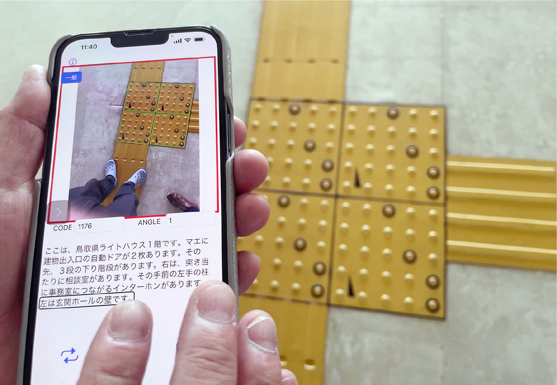 スマートフォンでコード化点字ブロックを撮影している画像